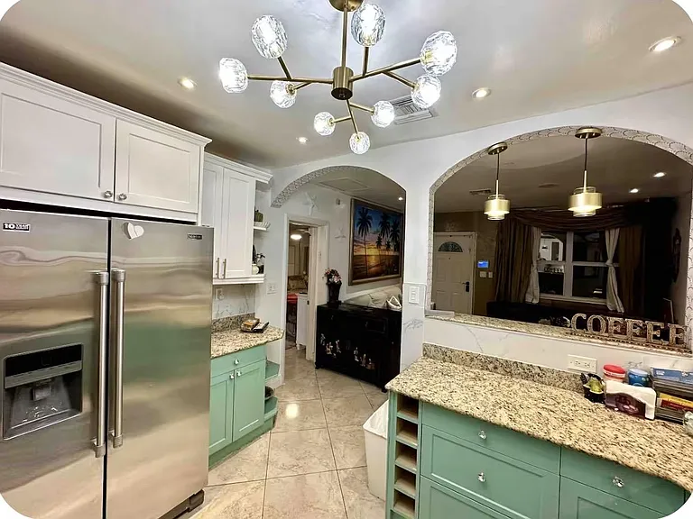 Updated kitchen with granite counters, stainless refrigerator, ample cabinetry, and open pass-through to the living area.