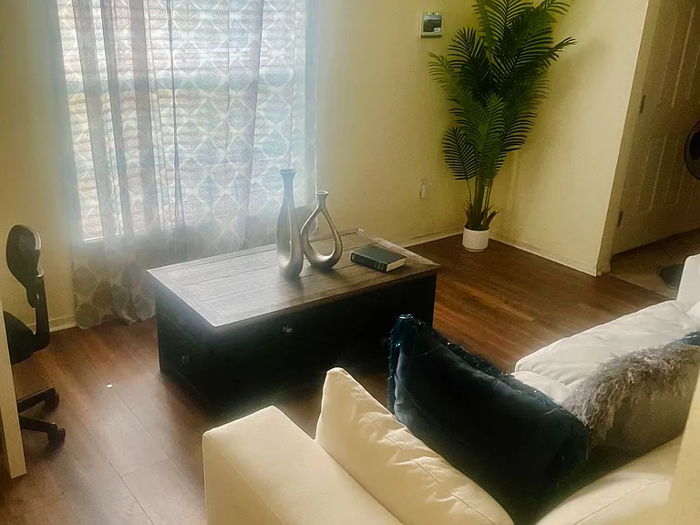 Open living area with a large window, wood-look flooring, and space for comfortable seating and a coffee table.