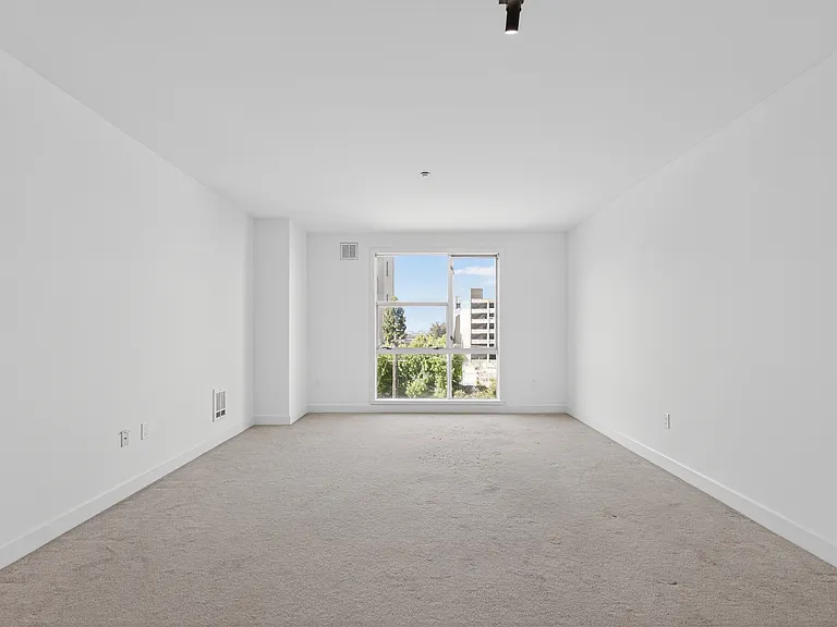 Long living room layout with natural light, updated lighting, and space for distinct seating, dining, and flexible-use areas.