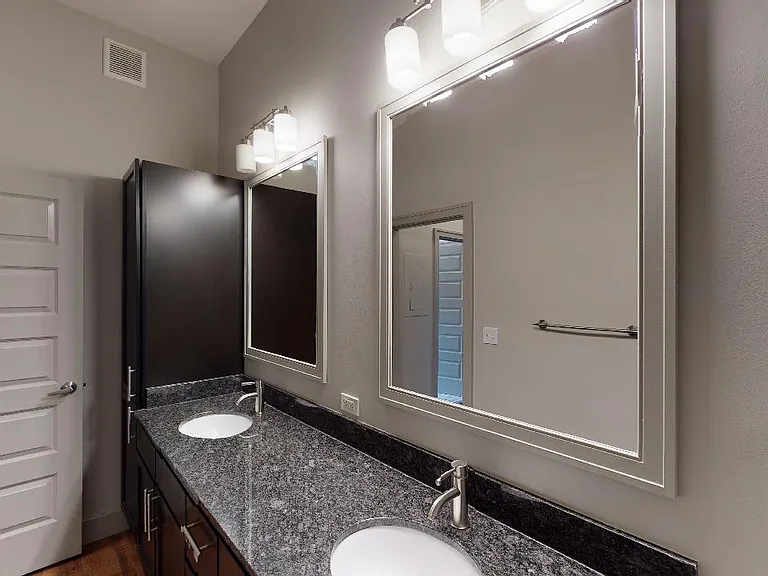 Apartment bathroom with wood-style flooring and double sinks.