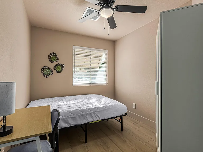 Actual bedroom: full bed, desk, chair, lamp, fan, closet.