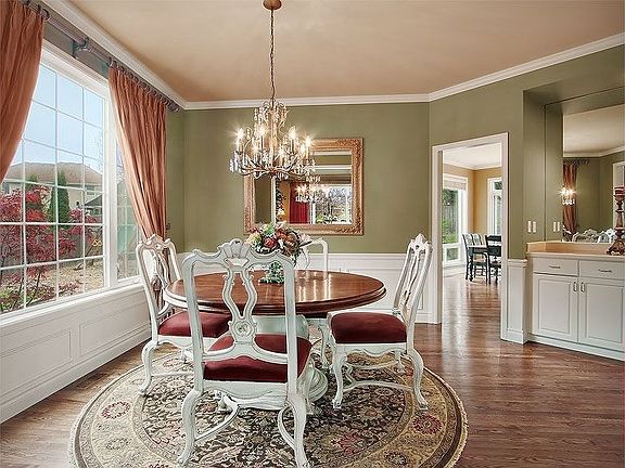 Dining room with glittering chandelier, built-in buffet & silk drapes.