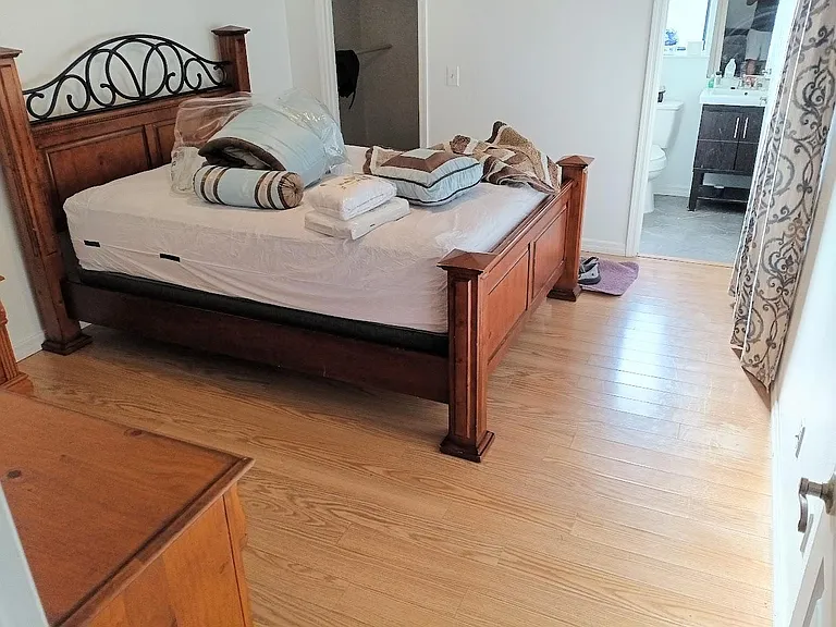Spacious bedroom with a large bed, hardwood floors, and convenient access to an adjacent full bathroom.