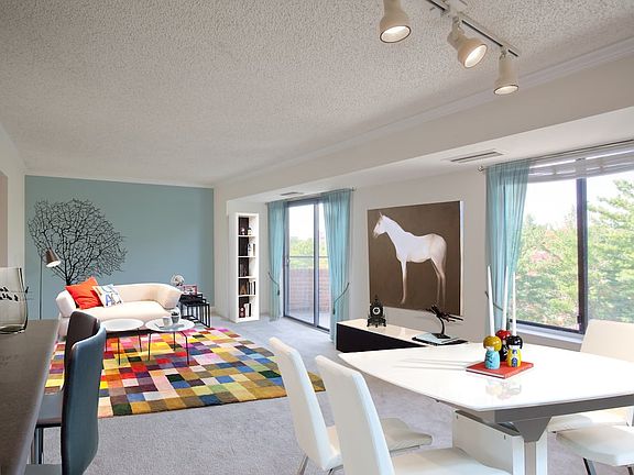 Living and dining areas with accent wall, balcony access and carpeted flooring