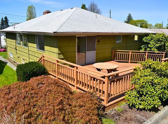 Back of the home with nice deck leading out to grassy yard and garage.