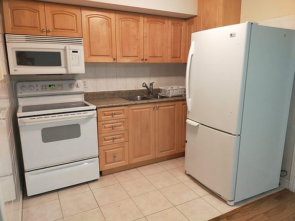 Kitchen with ceran cooktop electric range, microwave range hood, large full size refrigerator and double sink