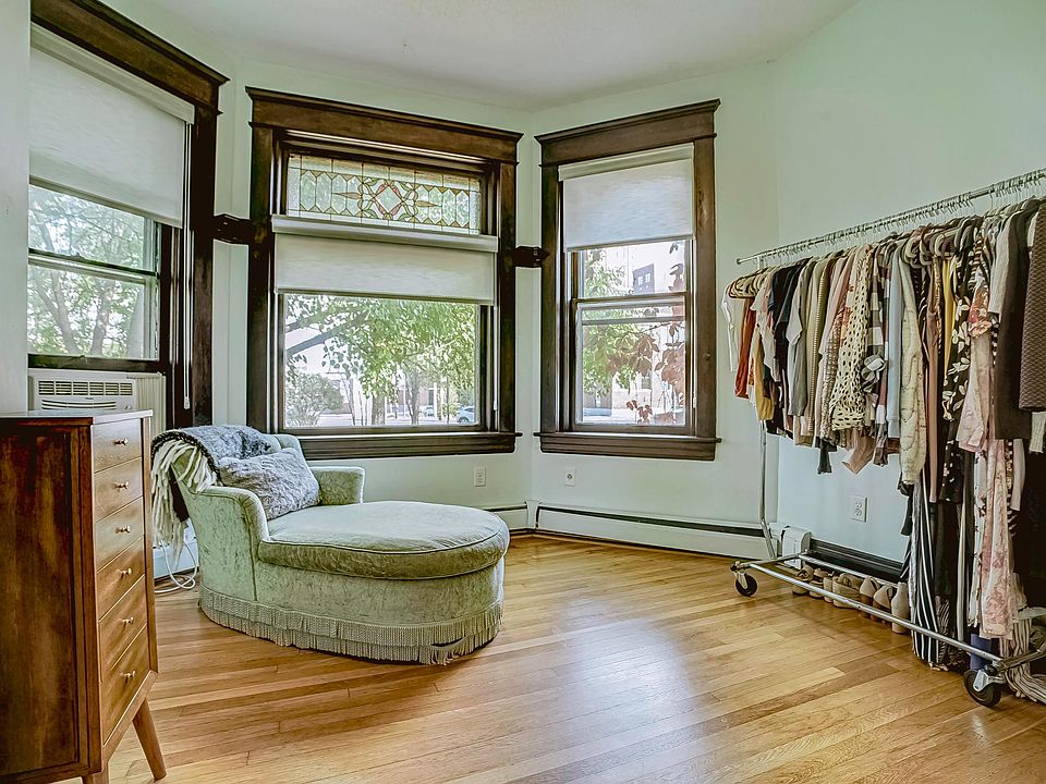 Second bedroom currently being used as a dressing room, featuring a large bay window and hardwood floors.
