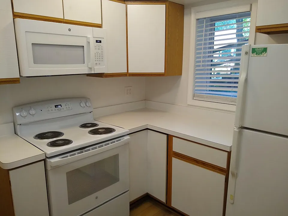 Kitchen with new flooring, stove and microwave. The washer and dryer are off the kitchen.