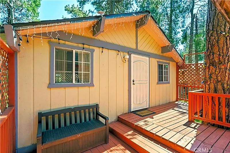 Charming front porch deck with gazebo for shade with enclosed fence in yard.