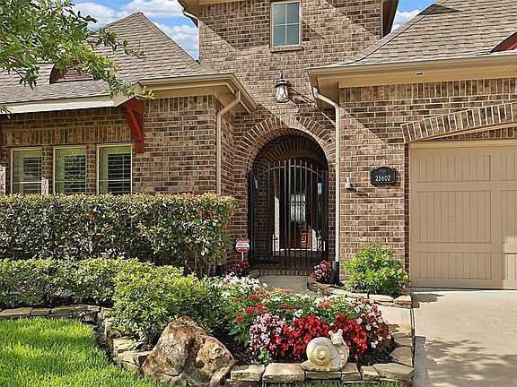 As you get closer to the entryway, you will love the stone lined flower beds, the painted wood corbel accents, accent brick design work, carriage house light fixtures, composite wood decorator garage door and the ornate wrought iron entry gate.