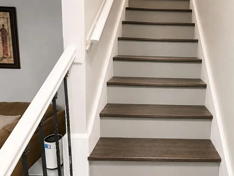 Clean interior stairwell with hardwood-style treads, sturdy handrails, and an open landing connecting the home's levels.