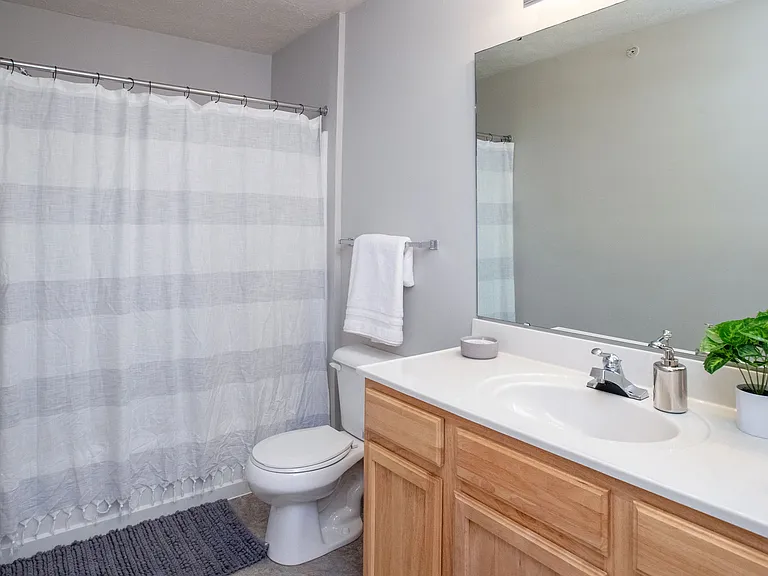 Bathrooms with wood-style flooring, spacious vanities, and oversized mirrors.