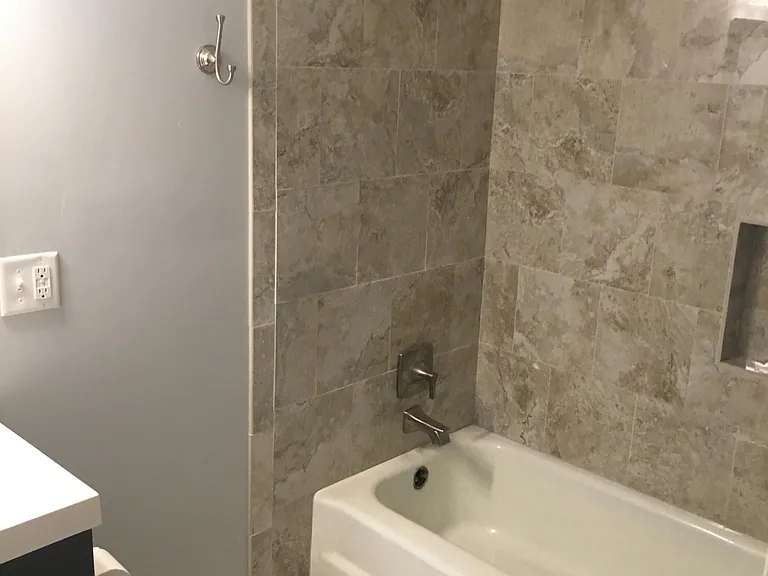 Full bath with new lights, toilet, vanity, sink, counter top, faucets, tile floor and shower surround.