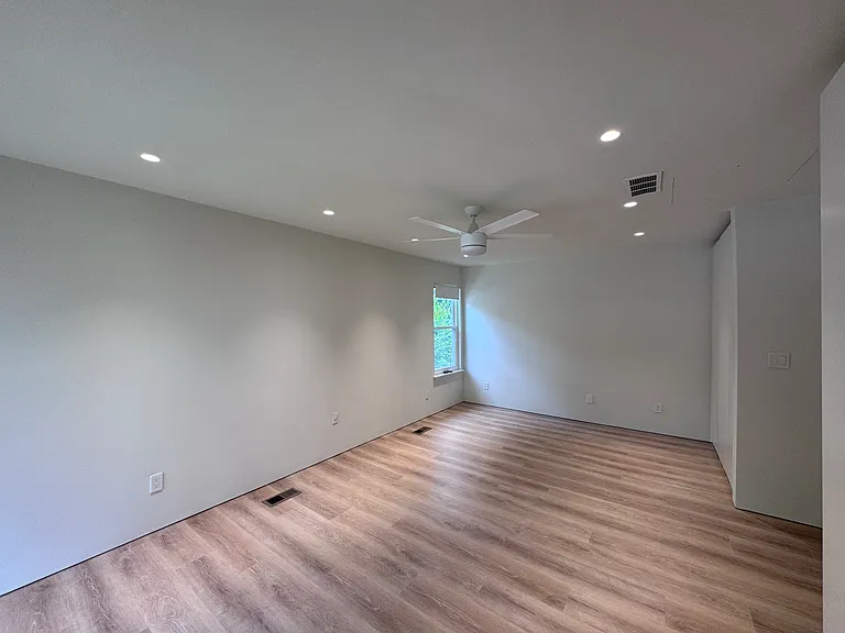 Bedroom 2 - Bright bedroom with recessed lighting, ceiling fan, and warm wood-look flooring.