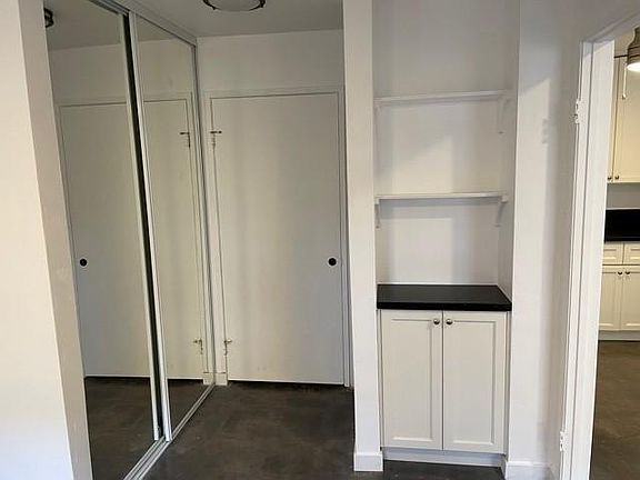 Bedroom entry and mirrored closet doors. Built in cabinet with area for phone charger and keys