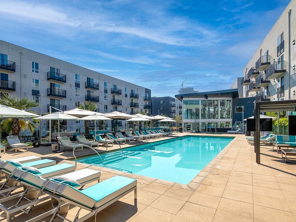 a swimming pool with lounge chairs and umbrellas at an apartment building