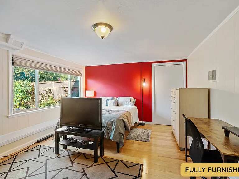 Downstairs is a large bedroom with ensuite full bathroom, queen bed, smart TV, sitting area, wall table, desk & chair, dresser, XL closet, large windows and an exterior door onto the backyard. Also connects to the laundry and bonus space.