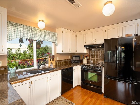 Solid surface granite counters in U-shaped kitchen with tiled backsplash.  Sink looks out onto cedar deck and back yard. Private and charming.