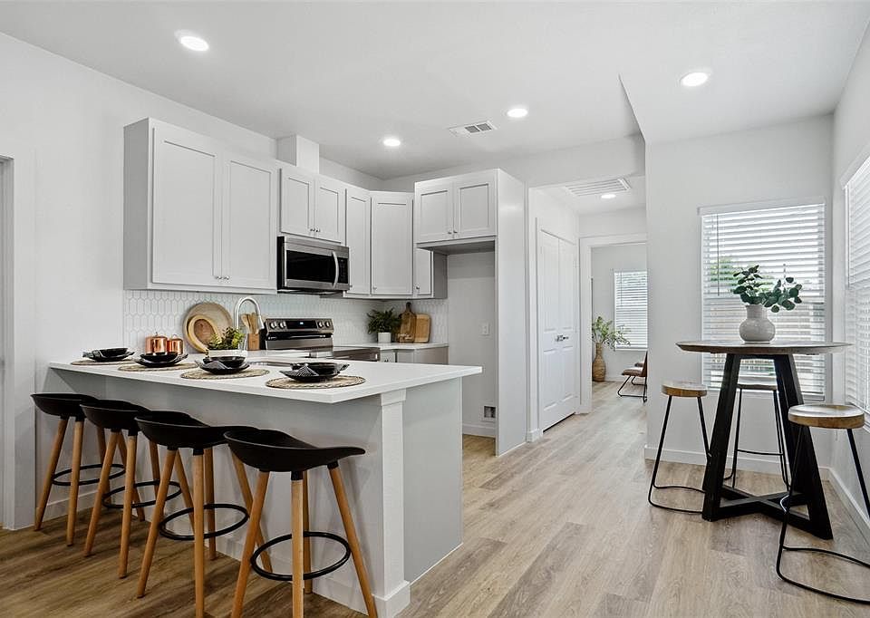 Kitchen with a peninsula, backsplash, visible vents, a kitchen bar, and appliances with stainless steel finishes