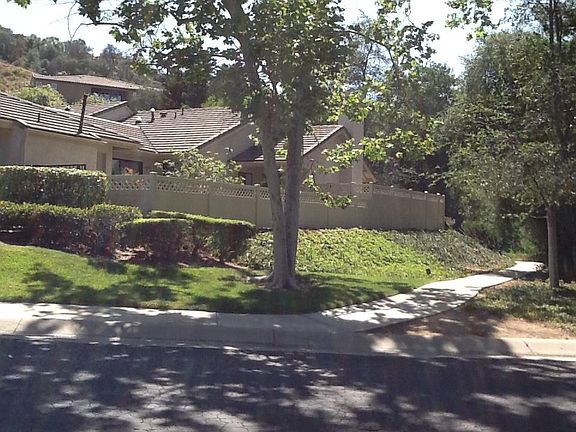 Street view of house with a walkway through a tree lined path to get to the community pool.