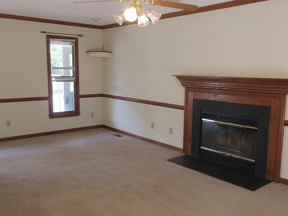 The living room includes a ceiling fan, wood-burning fireplace, built-in speaker stands, windows facing the front yard and (not shown here) a door to the back deck!