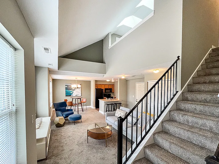 View from 1st-floor bedroom past staircase to open-plan great room with living, dining, and kitchen areas
