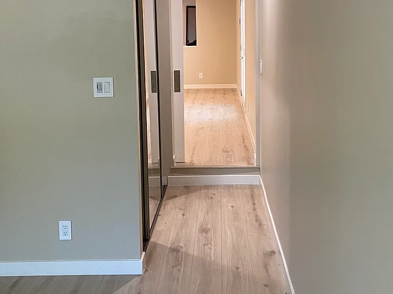 View from front bedroom to main Area showing hallway with Concealed Mirrored Door Closet