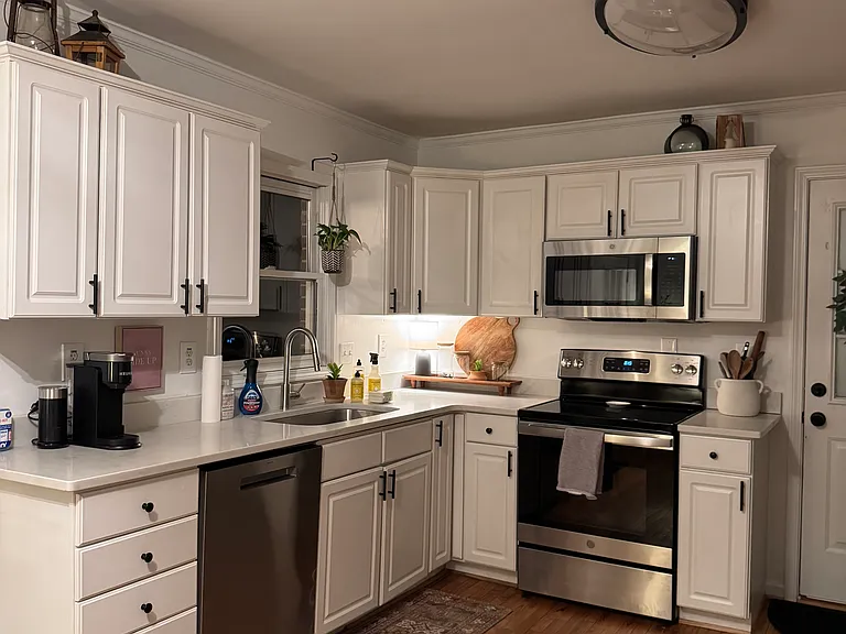 Spacious Kitchen, stainless steal appliances. Original wood floors throughout home. Left - french doors to backyard. Right of oven - garage door.