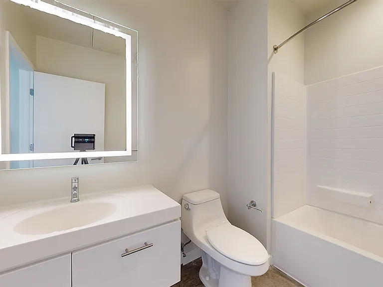 Apartment bathroom with LED vanity mirror.