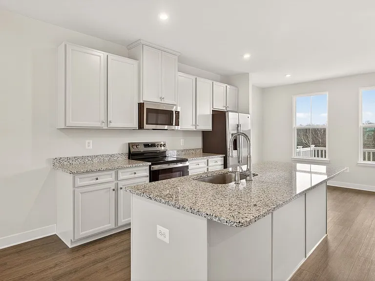 Closer image of the kitchen: granite countertops stainless steel appliances, large island with deep sink