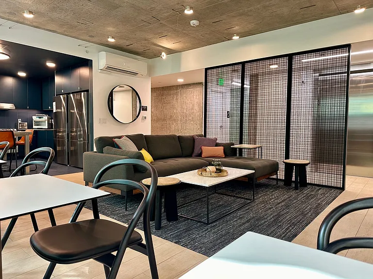Relax in this stylish living room at Anker Ballard, featuring a gray sofa, TV, and contemporary decor that creates a welcoming atmosphere.