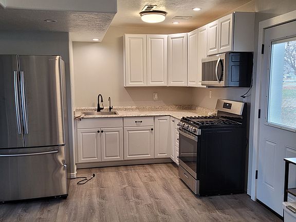 Kitchen area. Stainless steel gas stove sits where the shelf unit is underneath microwave. Full-size stainless refrigerator sits to the left in this photo.