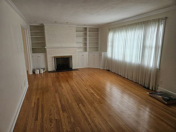 Freshly painted living room with large window for lots of natural light and a gas fireplace. Well maintained hardwood floors. Shelving and under storage.
