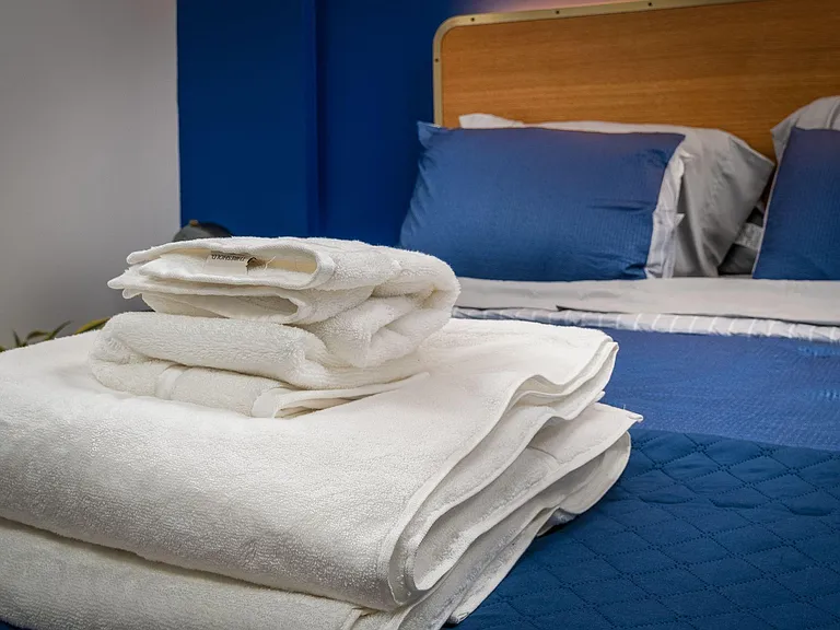 Neatly furnished bedroom featuring a comfortable bed with coordinating linens and a streamlined headboard for easy rest.