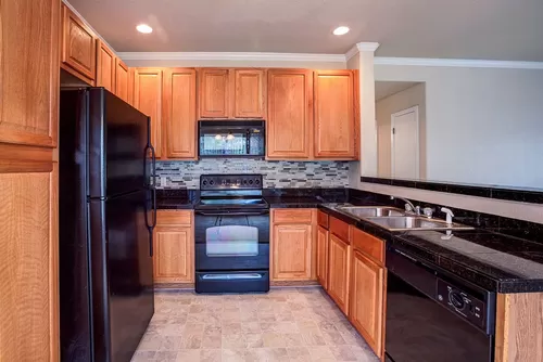 Kitchen featuring all black appliances, large Formica counter tops, and walnut cabinets. - Summerfield