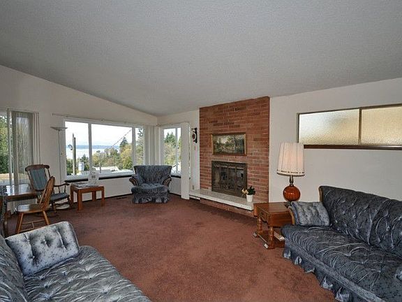 Open and light filled living room has high vaulted ceilings, gas fireplace, double pane windows, and a calm and peaceful view