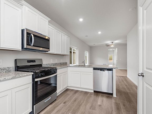 The kitchen has stainless steel appliances and plank flooring.