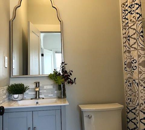 Ensuite bathroom with gray shaker cabinetry, tile floors, 5 foot shower with white subway tile and glass/marble accents, beautiful lighting and accessories.