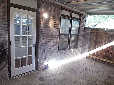 Covered private patio with stone tile flooring and direct access to parking