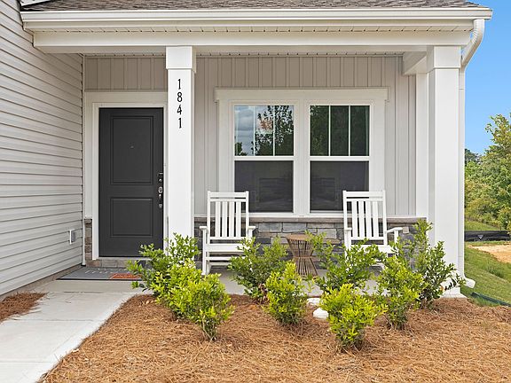 A white house with a porch and two white rocking chairs.