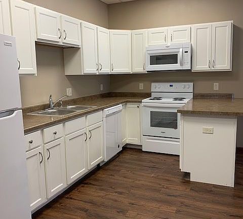 Modern kitchen with elegant white cabinetry, stainless steel appliances, and rich wood flooring, perfect for culinary creativity.