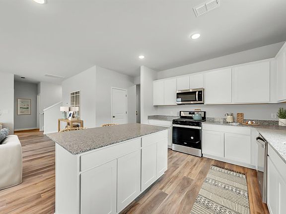 The oversize kitchen island provides exceptional granite countertop and cabinet space. Model Home Re