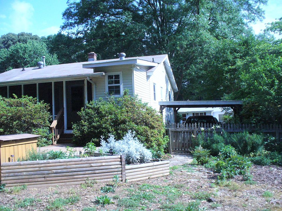 Back of house with carport, herb garden, and flower bed