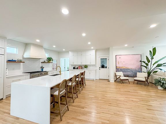 The entry reveals an open-plan layout with clear sightlines to the kitchen and living areas. Natural light and an oversized island create a bright, cohesive space.