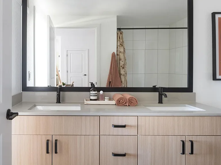 A spacious double vanity with light wood cabinetry, matte black accents, and generous counter space for an elevated daily routine.