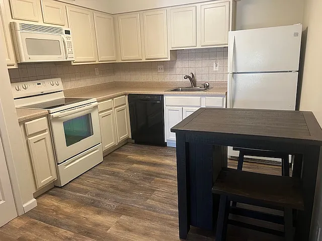 Kitchen with wood-like floors and eating area.