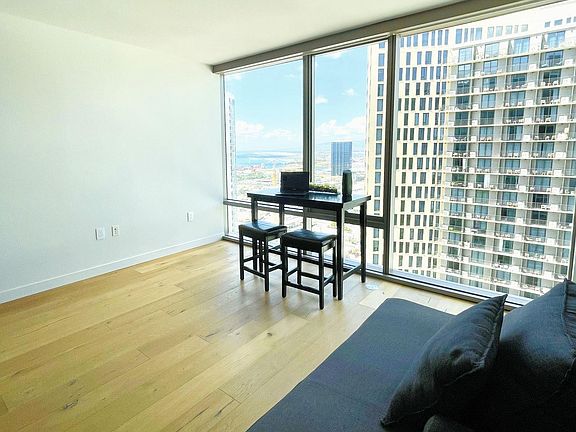 Spacious living room with hardwood floors and ocean view. Note: full length floor to ceiling motorized window treatments