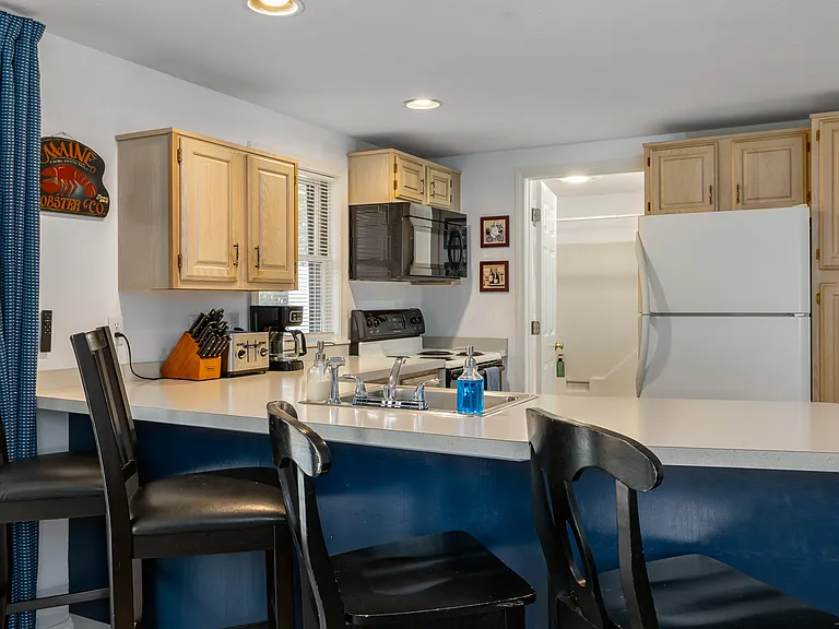 Kitchen. Refrigerator, electric stove and oven, microwave, coffee maker, toaster, and full plates, bowls, glasses, mugs, forks, knives, spoons, pots and pans, and kitchen utensils.