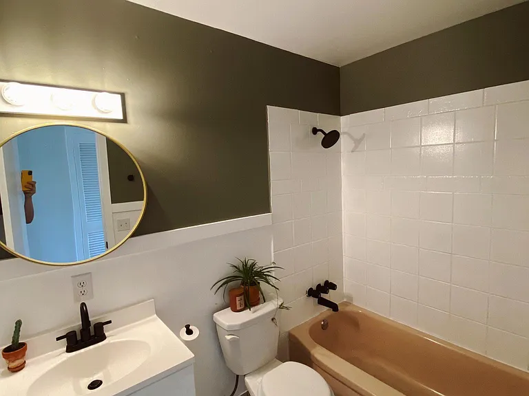 Newly remodeled bathroom with fresh paint and new fixtures highlighting an original, pale pink vintage bathtub.