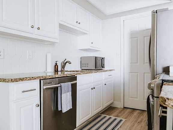 Kitchen equipped with new appliances (dishwasher, oven, fridge), connected to washer/dryer room